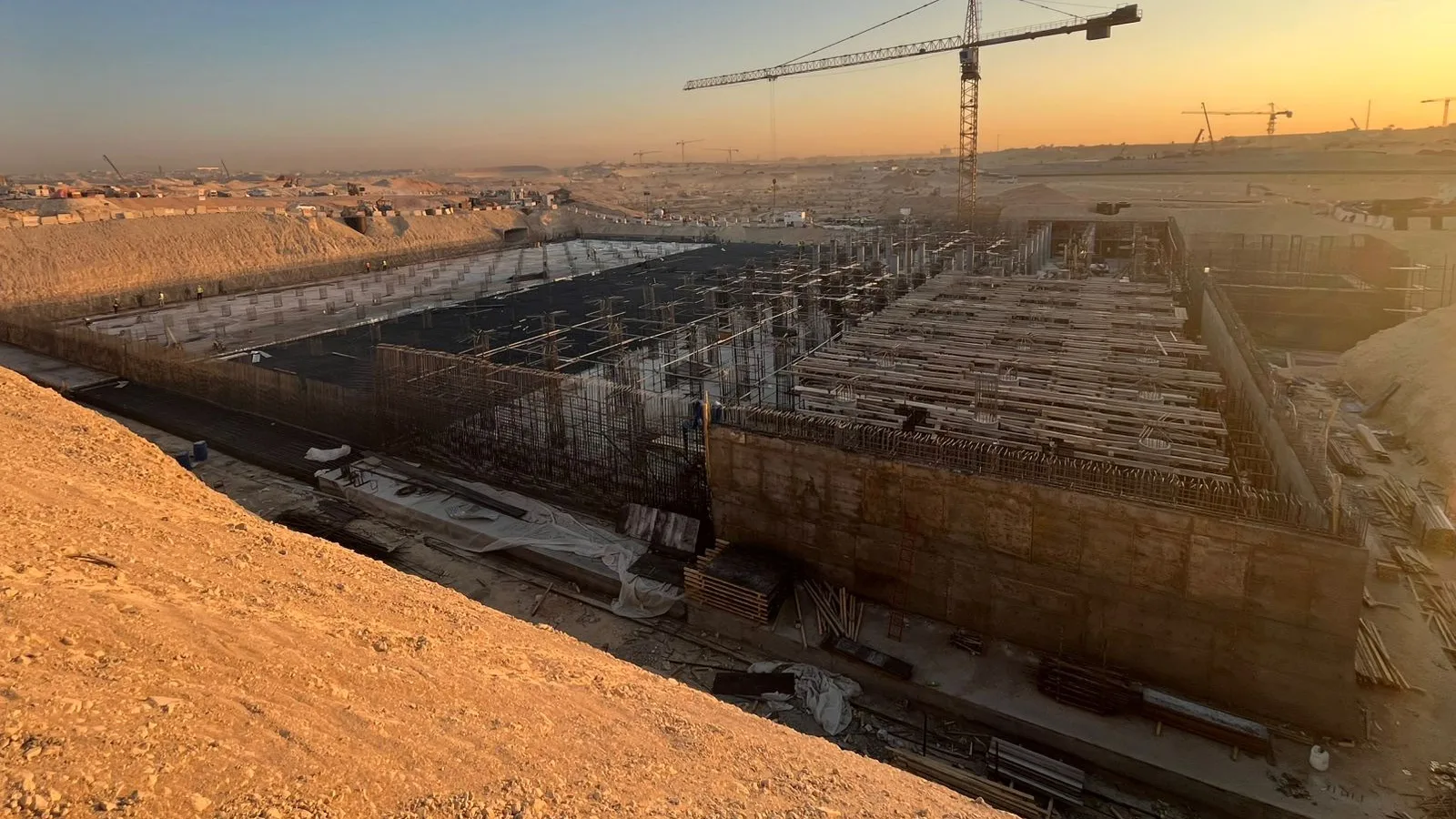 موقع إنشاء عند الغروب مع رافعة برجية